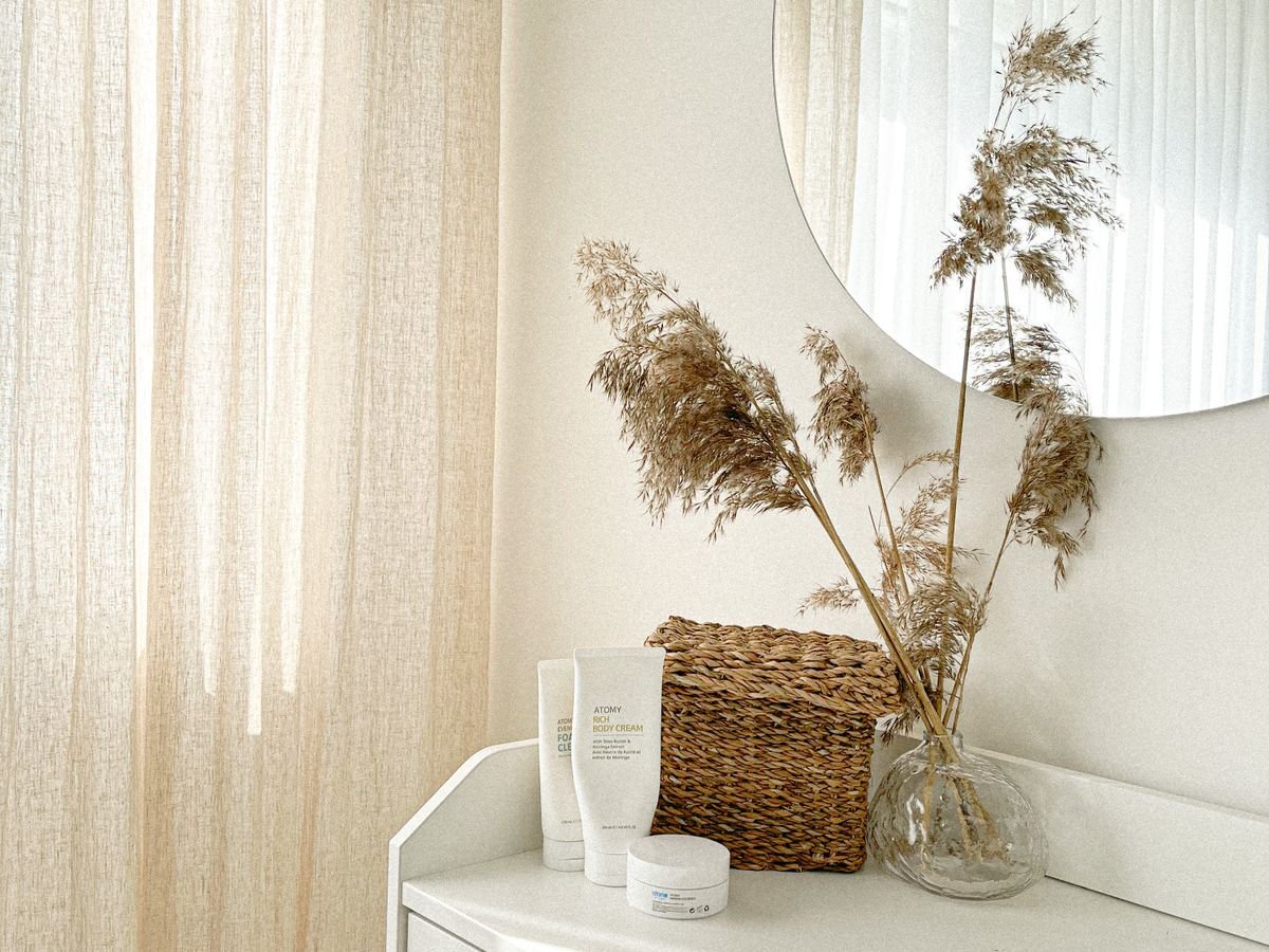 Un coin beige avec des herbes de la pampa, un panier tressé et un miroir rond.